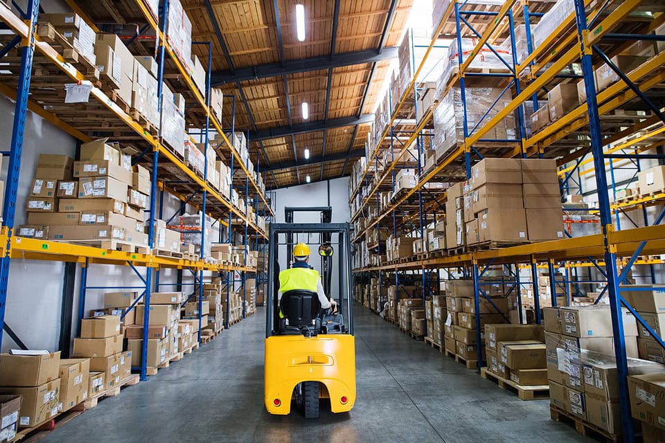 Man Forklift Driver Working In A Warehouse. Rear View.